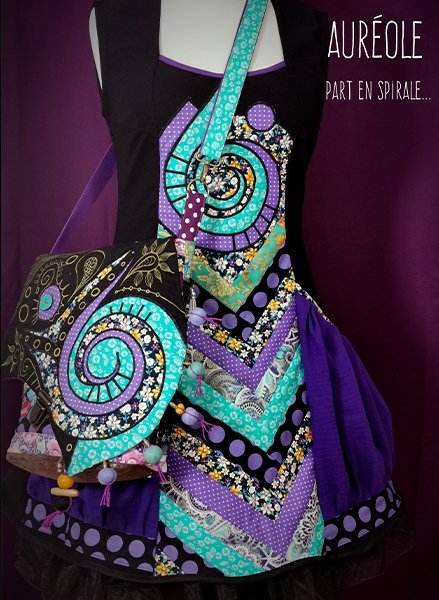 robe à poches bouffantes, violet et turquoise, avec une spirale sur la poitrine. A l'épaule, le sac assorti.